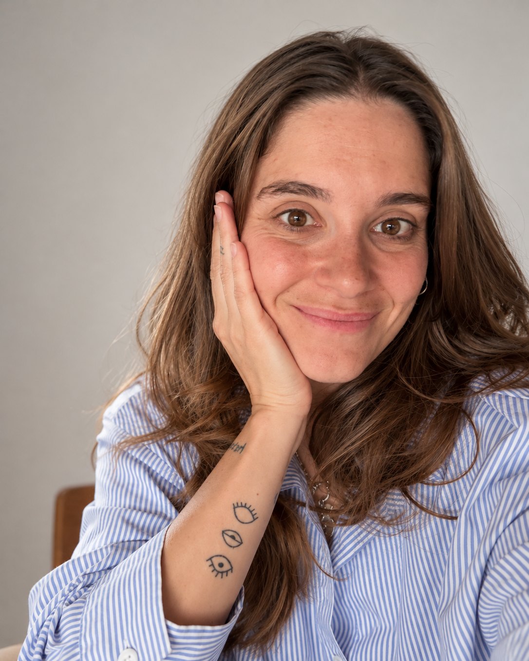 Camila Videla sonriendo, con la mano en la mejilla